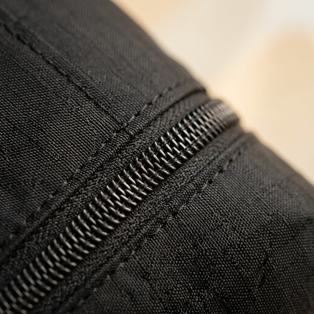 Macro detail of black ripstop nylon fabric and heavy-duty zipper on a Bugatti compression packing cube.